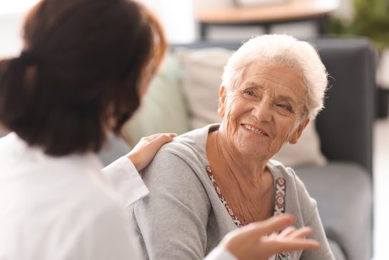 Vanhempi nainen keskustelee hoitajan kanssa.