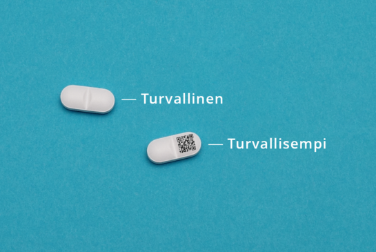 Turkoosin sinisellä tasaisella taustalla näkyy kaksi lääkepilleriä, joissa toisessa on qr-koodi. Pillerissä ilman koodia vieressä on teksti 