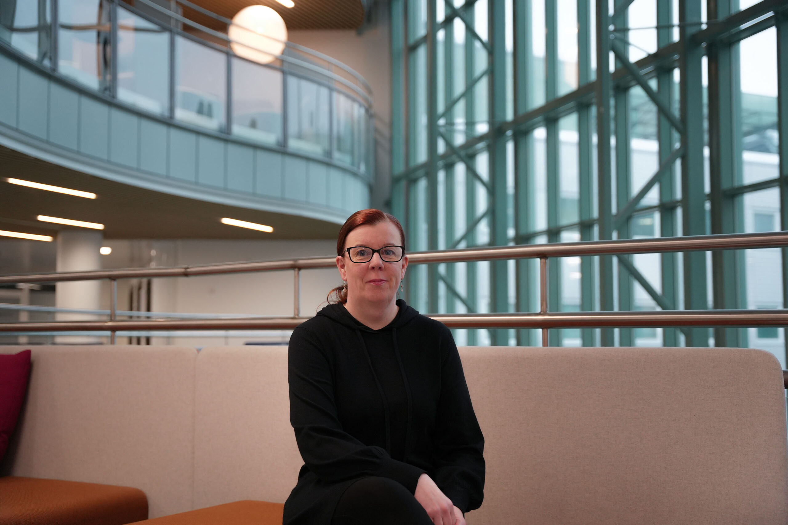 Petra Haataja istuu penkillä porrasaulassa